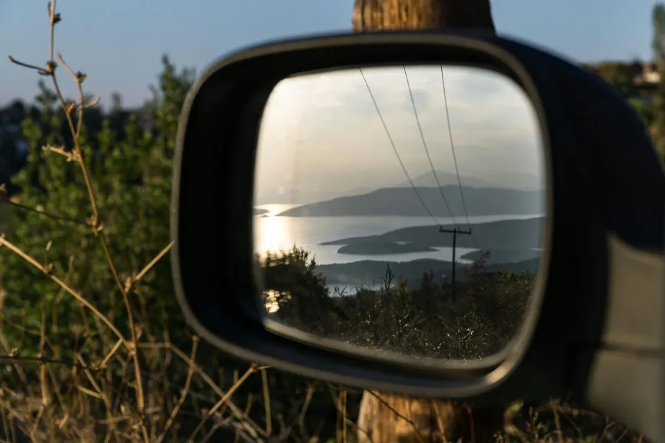 Beautiful landscape reflection in a car side mirror during sunset in Argalasti, Greece.