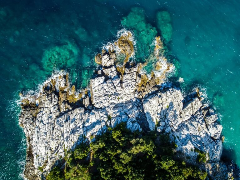 Stunning aerial shot of a rocky coastline in Greece with vibrant turquoise waters, showcasing natural beauty.